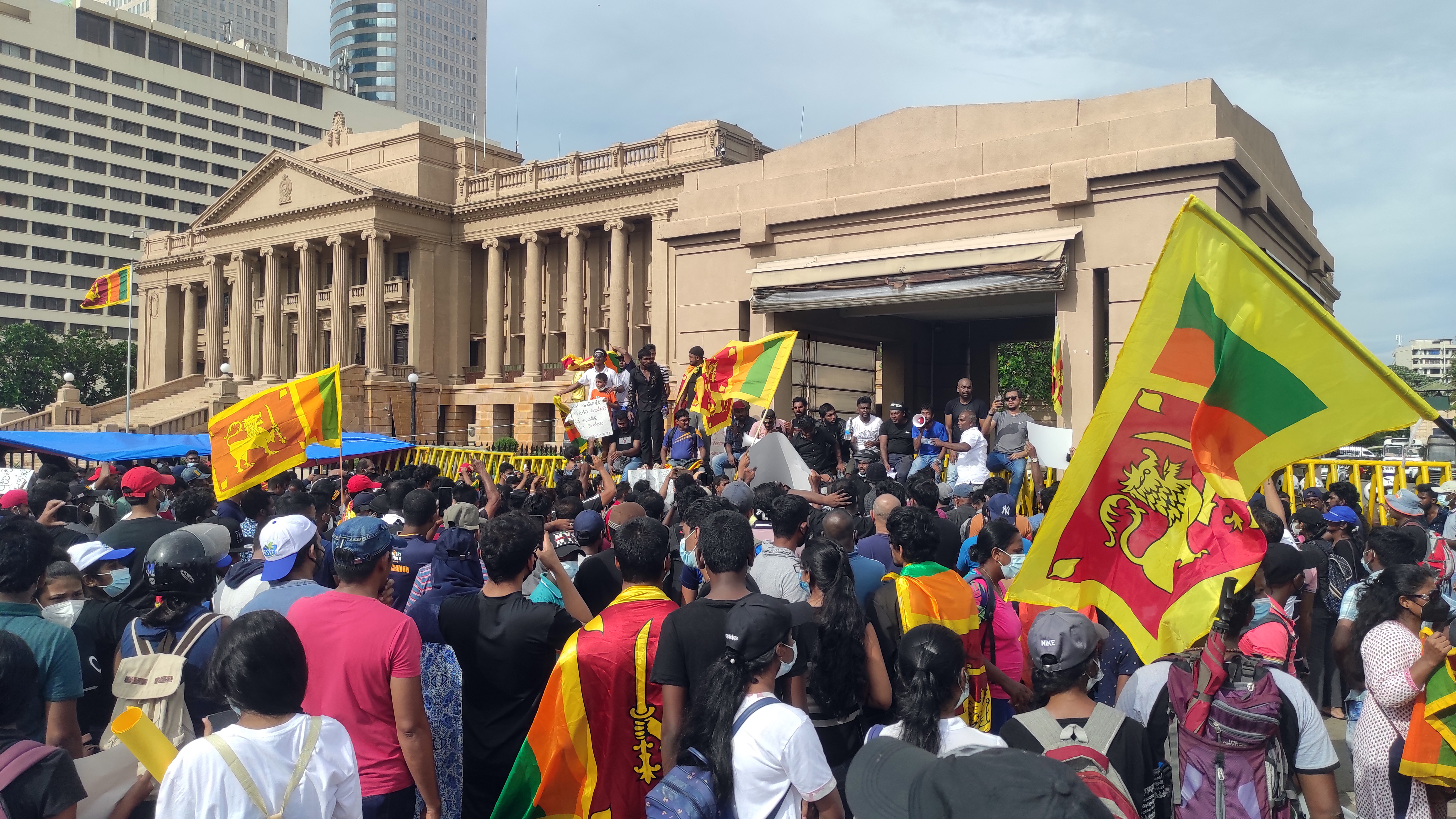 Crowds waving Sri Lankan flags outside the colonnaded Presidential Secretariat in Colombo