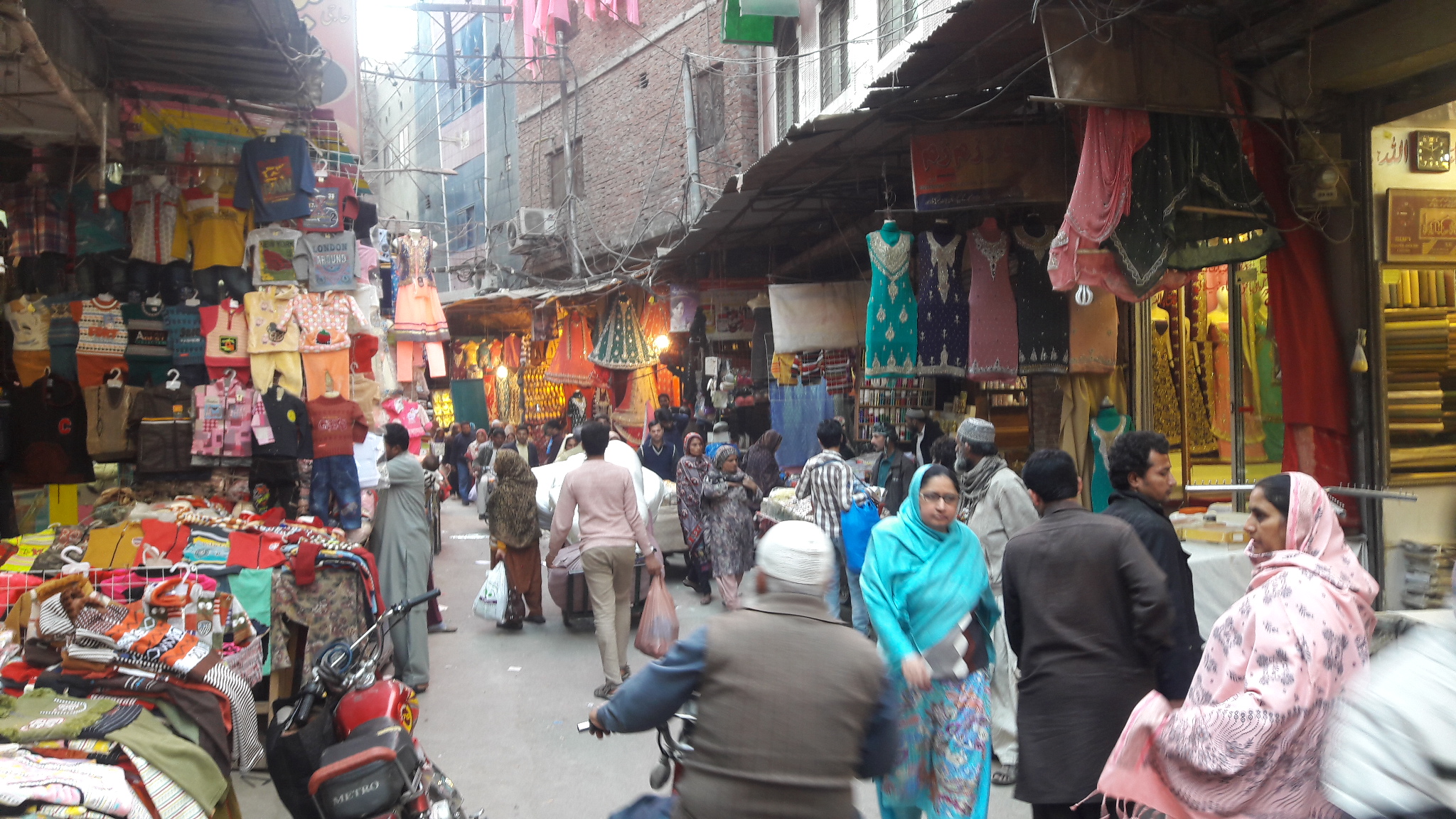 Shoppers walking through a crowded clothing bazaar in Lahore
